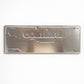 Backside of Coimbra metal souvenir sign showing engraved city skyline and lettering on a metallic surface
