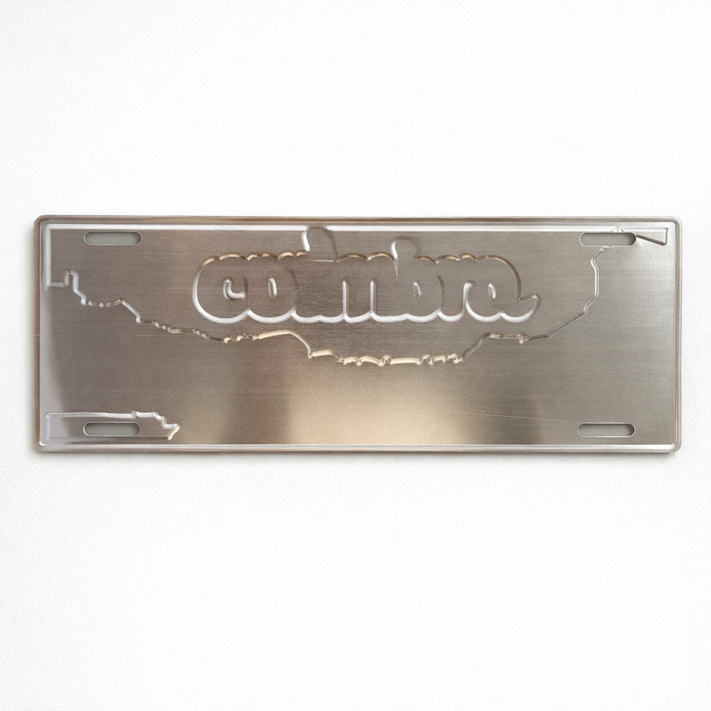 Backside of Coimbra metal souvenir sign showing engraved city skyline and lettering on a metallic surface