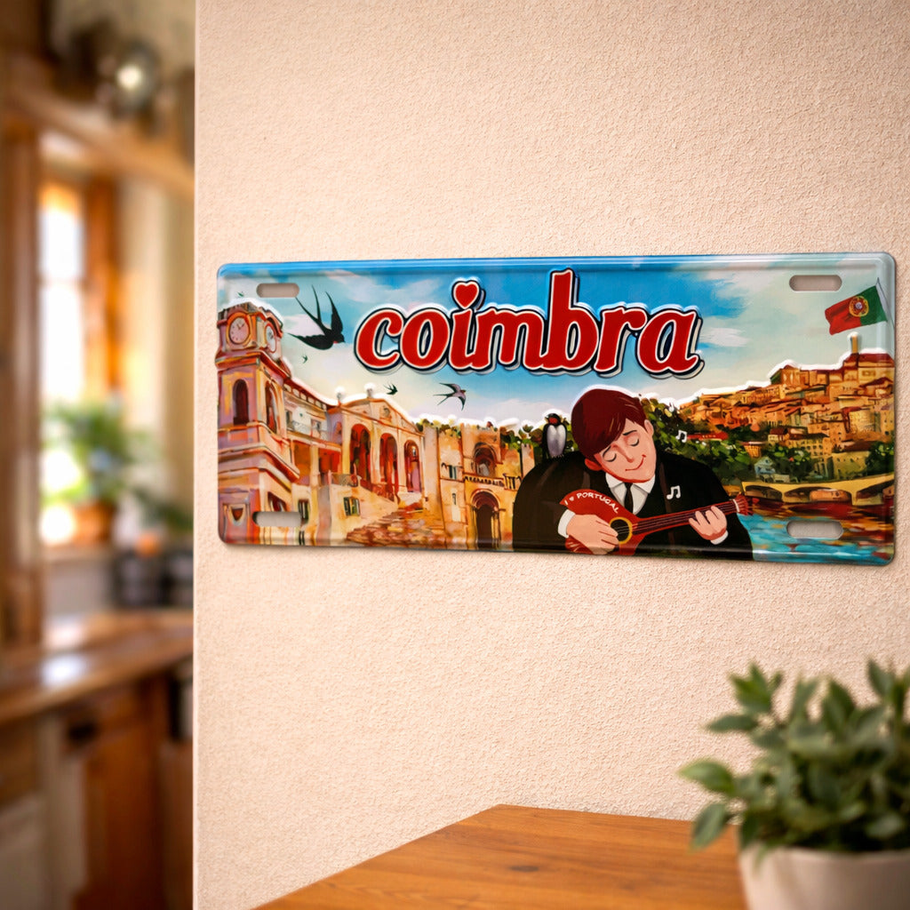 Coimbra metal souvenir sign mounted on a wall featuring university architecture, a fado musician and city landscape