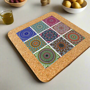 A square cork coaster, ideal as a souvenir, displays a 3x3 grid of nine vibrant and intricate mandala patterns. The designs feature colors like green, blue, orange, and pink, each standing out against a white background.