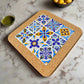 A square tile coaster featuring intricate blue, yellow, and white patterns, including floral and geometric designs arranged in a 3x3 grid. This delightful Portuguese souvenir has a sturdy cork base and is set on a white surface.