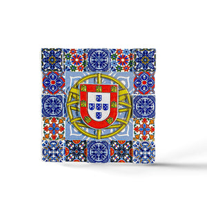 A square mosaic magnet featuring intricate blue, red, yellow, and green tile patterns surrounding the central emblem of Portugal. The emblem includes a shield with five smaller shields arranged in a cross, topped with a yellow border containing red castles—a perfect souvenir from Portugal.