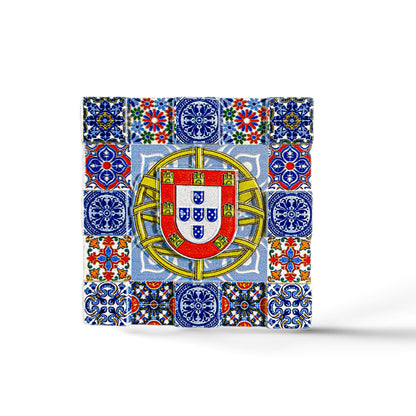 A square mosaic magnet featuring intricate blue, red, yellow, and green tile patterns surrounding the central emblem of Portugal. The emblem includes a shield with five smaller shields arranged in a cross, topped with a yellow border containing red castles—a perfect souvenir from Portugal.