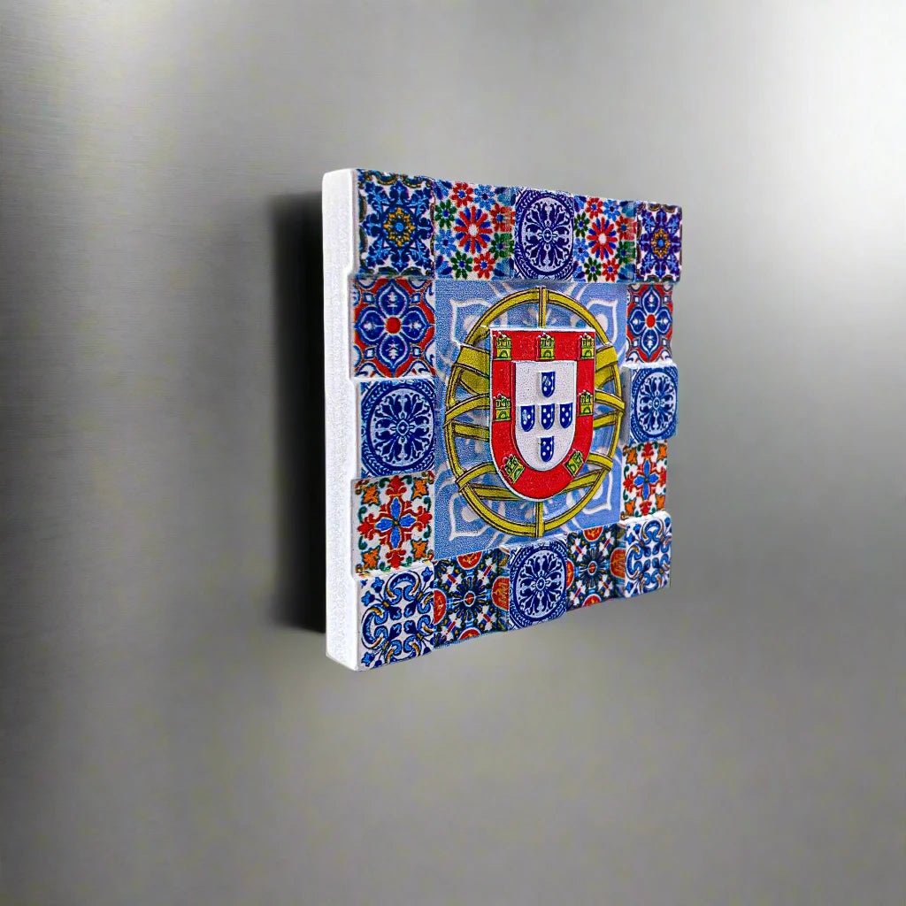 A square mosaic magnet showcasing detailed blue, red, yellow, and green tile patterns around the central emblem of Portugal. The emblem features a shield with five smaller shields arranged in a cross, bordered by a yellow frame with red castles—an ideal souvenir from Portugal.