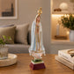 Elegant Our Lady of Fátima souvenir figure displayed on a wooden table, highlighting the detailed white mantle and religious symbolism.