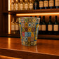 Guimarães souvenir shot glass decorated with colorful Portuguese azulejo tile patterns displayed on a wooden bar counter