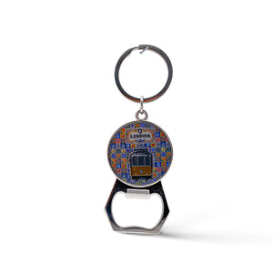 A keychain with a bottle opener attached. The round element shows a colorful illustration of a Lisbon tram with the word "Lisboa" at the top. This charming souvenir features a background pattern reminiscent of traditional Portuguese tiles.