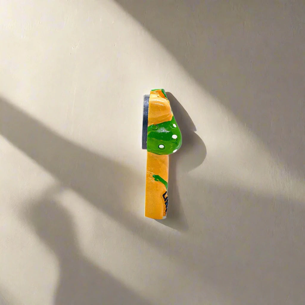 A charming magnet featuring a bikini girl figurine dressed in a green bikini with white polka dots. "LISBOA" appears on the left side of the bottoms, while a small Portuguese flag decorates the right. The figurine stands out against a plain white background.
