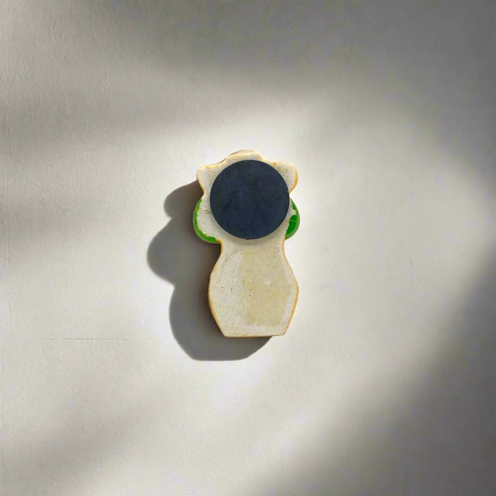 A decorative magnet of a bikini girl wearing a green polka-dotted bikini. The word "LISBOA" is written on the left side of her bottoms, with a small Portuguese flag on the right, creating a delightful souvenir against the white backdrop.