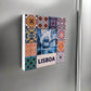 A vibrant collage of traditional Portuguese tiles surrounds a central image of a tram winding through a narrow Lisbon street. The word "LISBOA" is boldly displayed at the bottom. The tiles feature intricate patterns in shades of blue, red, and orange, making this magnet an ideal Portugal souvenir.