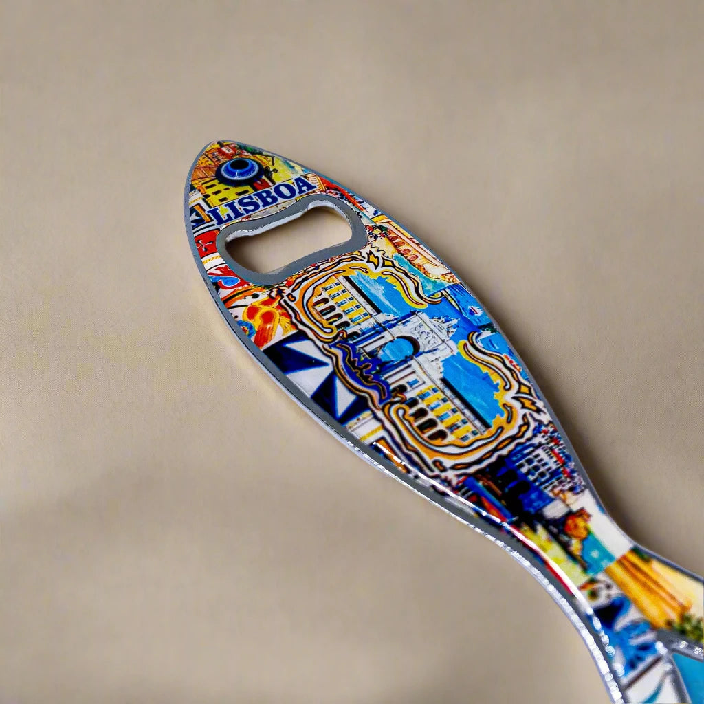 A metal bottle opener shaped like a sardine, decorated with vibrant, intricate designs including a famous Lisbon landmark and the word "Lisboa." The opener hole is cleverly positioned where the fish’s eye would be, making it a delightful Portugal souvenir.