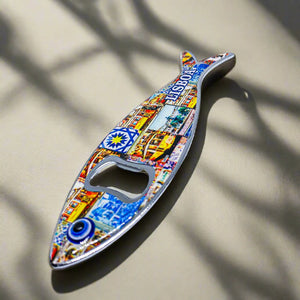 A metal bottle opener in the shape of a sardine, featuring detailed and colorful designs, including a notable Lisbon landmark and the word "Lisboa." The opener hole is creatively placed at the fish's eye, making it a unique souvenir from Portugal.