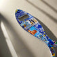 A sardine-inspired metal bottle opener, decorated with colorful and detailed artwork that includes a Lisbon landmark and the word "Lisboa." The opener hole is placed at the fish's eye, making it a delightful Portuguese souvenir.