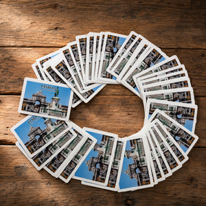 Lisbon souvenir playing cards arranged in a circular spread on a wooden table, featuring a Praça do Comércio design inspired by one of Lisbon’s most iconic monuments.