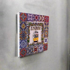 A vibrant decorative tile featuring intricate blue, yellow, and green patterns frames a central image of a classic yellow tram with the word "LISBOA" displayed above. This beautiful souvenir reflects the essence of Portugal, evoking the charm of traditional Portuguese azulejos.