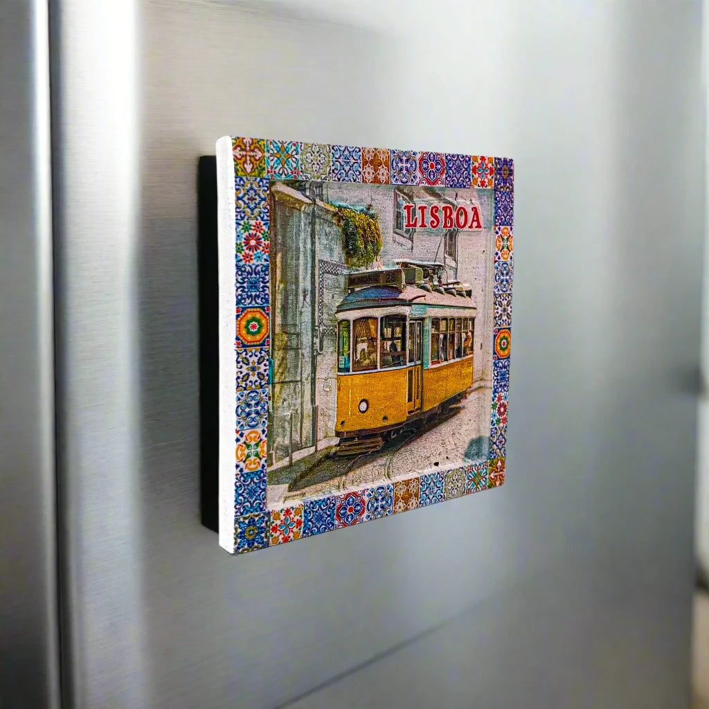 A decorative tile magnet showcases a classic yellow Lisbon tram, framed by a vibrant and detailed mosaic pattern. The word "Lisboa" is prominently positioned in the top right corner, highlighting the city's name and making it an ideal souvenir from Portugal.