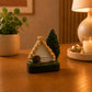 Detailed Madeira souvenir magnet showcasing a traditional Santana cottage with colourful windows, a straw roof, and lush greenery.