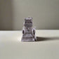 A small, intricately crafted replica of Lisbon's Belem Tower is shown with "PORTUGAL" inscribed in gold at the base. Set against a white background, the detailed architecture is beautifully highlighted.