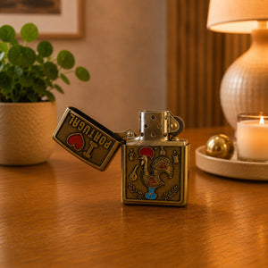 Open metal petrol lighter with Portugal rooster artwork, antique brass finish, and traditional wind-resistant mechanism.