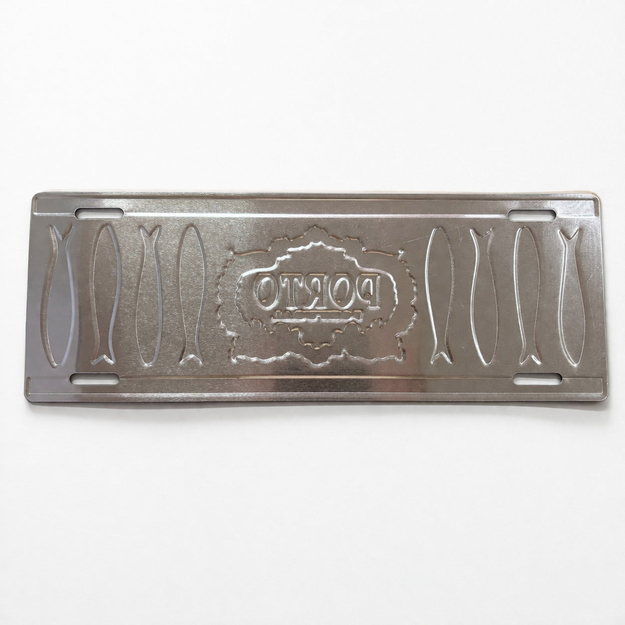 Backside of Porto metal souvenir sign showing engraved sardine shapes and embossed design on a metallic surface