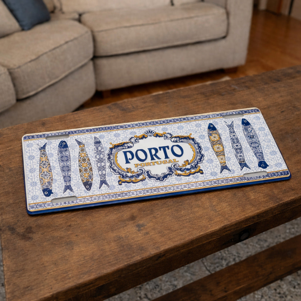 Porto metal souvenir sign placed on a wooden table showing stylized sardines and classic Portuguese tile patterns