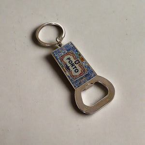 A rectangular keychain with a bottle opener at the base and a metal ring at the top. This eye-catching souvenir showcases a vibrant, detailed design with the word "Porto" prominently displayed in the center, capturing the essence and beauty of this charming Portuguese city.