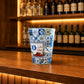 Decorative Porto souvenir shot glass with traditional rabelo boat illustration and blue Portuguese tile artwork displayed on a wooden bar counter