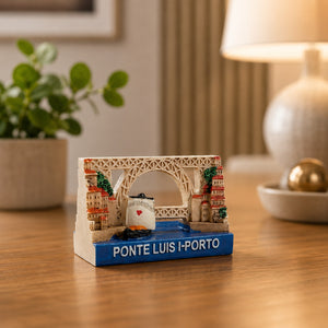 Decorative Porto magnet featuring the famous Dom Luís I Bridge, Ribeira district architecture, and a traditional wine transport boat in a realistic miniature design.