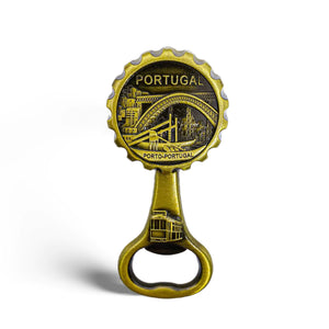 A decorative brass bottle opener featuring an engraved design of Porto, Portugal. The circular top showcases a detailed illustration of the Dom Luís I Bridge, a traditional tram, and cityscapes, with the inscriptions "PORTUGAL" and "PORTO-PORTUGAL.