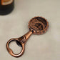 A decorative brass bottle opener featuring an engraved depiction of Porto, Portugal. The round top includes intricate illustrations of the Dom Luís I Bridge, a traditional tram, and city landmarks, with the words "PORTUGAL" and "PORTO-PORTUGAL" inscribed.