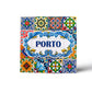 A square ceramic tile magnet features intricate, colorful patterns in blue, red, green, and yellow. The center reads "PORTO" in bold blue letters, surrounded by a decorative blue frame. The design is reminiscent of traditional Portuguese azulejos.
