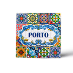 A square ceramic tile magnet features intricate, colorful patterns in blue, red, green, and yellow. The center reads "PORTO" in bold blue letters, surrounded by a decorative blue frame. The design is reminiscent of traditional Portuguese azulejos.