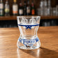 Back view of Porto women bikini style shot glass featuring blue decorative stripe and Porto azulejo souvenir artwork on wooden surface.