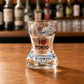 Front view of a Porto women bikini style shot glass with azulejo artwork, Porto landmarks, and I Love Porto text displayed on a wooden bar counter.