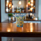 Portugal souvenir shot glass featuring intricate blue and yellow Portuguese tile designs placed on a wooden surface in a bar setting.