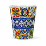 Portugal souvenir shot glass fully decorated with intricate blue and colorful Portuguese azulejo tile designs isolated on white background.