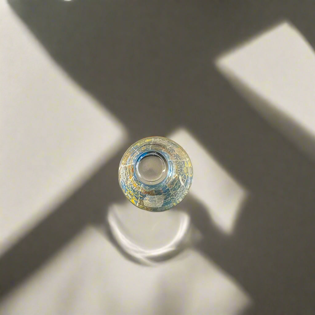 Top view of Portugal azulejo souvenir shot glass with colorful Portuguese tile patterns and artistic shadow reflections on a neutral background.