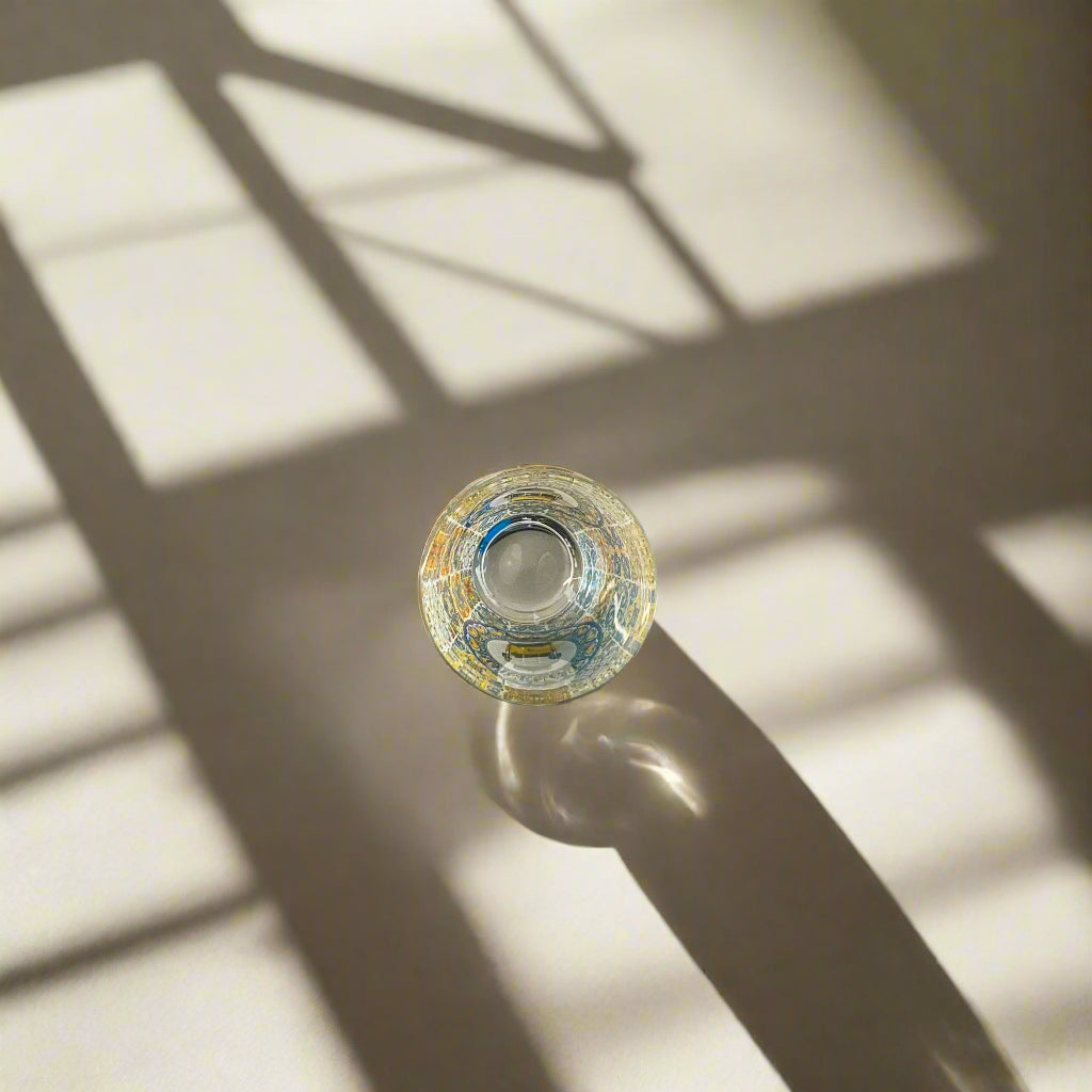 Top view of Portugal azulejo souvenir shot glass with colorful Portuguese tile patterns casting a shadow on a light background.