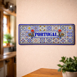 Portugal metal souvenir sign mounted on a wall displaying colorful Portuguese tile patterns with iconic Barcelos roosters