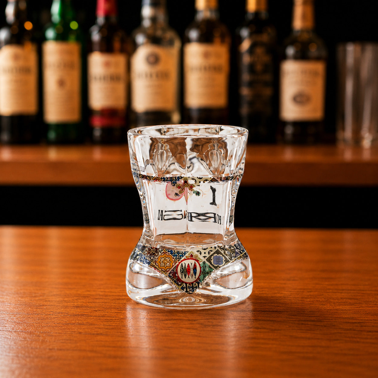 Back view of Portugal bikini style shot glass with colorful Portuguese tile pattern and transparent sculpted glass on wooden bar counter.