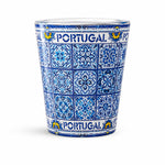 Portugal souvenir shot glass fully decorated with detailed blue Portuguese azulejo tile patterns isolated on white background.