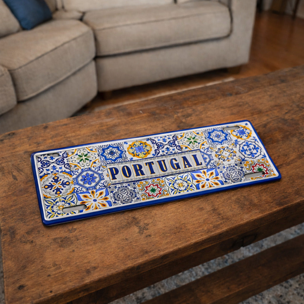 Portugal metal souvenir sign placed on a wooden table featuring traditional Portuguese tile patterns in blue and vibrant colors