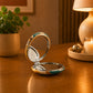 Open Portugal compact travel mirror with vibrant Portuguese landmark artwork, displayed on a wooden surface in a warm indoor setting.