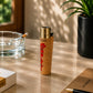 Portugal cork Clipper lighter with Portugal map artwork and regional cultural symbols photographed at an angle in a lifestyle setting with warm sunlight and decorative desk accessories.