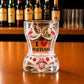 Front view of Portugal flamingo bikini style souvenir shot glass with I Love Portugal text and tropical flamingo design on wooden counter.