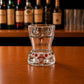 Back view of Portugal flamingo bikini style shot glass with floral tropical artwork displayed on wooden bar surface.