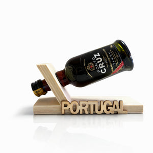Clean product view of Porto Cruz Tawny Port wine bottle balanced on a wooden floating stand with Portugal engraving.