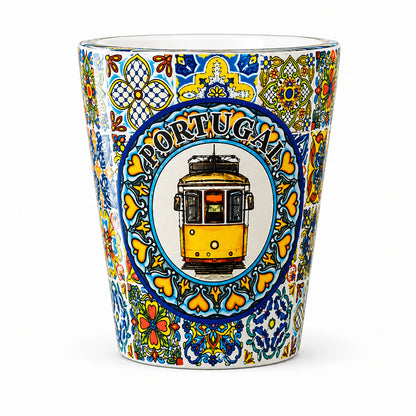 Transparent Portugal shot glass with Lisbon yellow tram illustration and detailed Portuguese azulejo tile artwork isolated on white background.