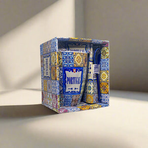 
A decorative boxed set featuring a ceramic coffee mug, dish, and spoon with traditional Portuguese blue and yellow tile patterns. The packaging showcases similar decorative tile motifs with the word "Portugal" prominently displayed on the mug and box—an ideal souvenir from Portugal.