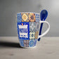 A vibrant ceramic coffee mug with a mosaic tile pattern and the word "PORTUGAL" prominently displayed in the center. The mug showcases intricate blue and yellow designs inspired by traditional Portuguese tiles and includes a small blue ceramic spoon attached to the handle, making it a unique souvenir.